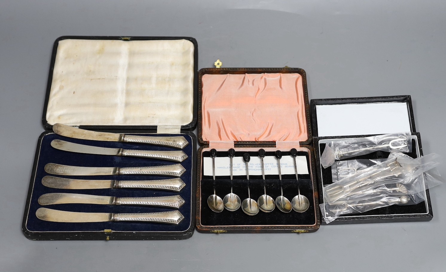 Three assorted cased sets including six silver handled tea knives, six bean end coffee spoons and six sterling cocktail forks.